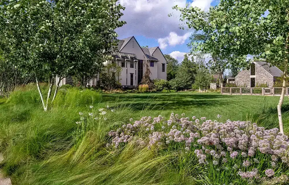 A lawn with grass and flowers in front of a house.