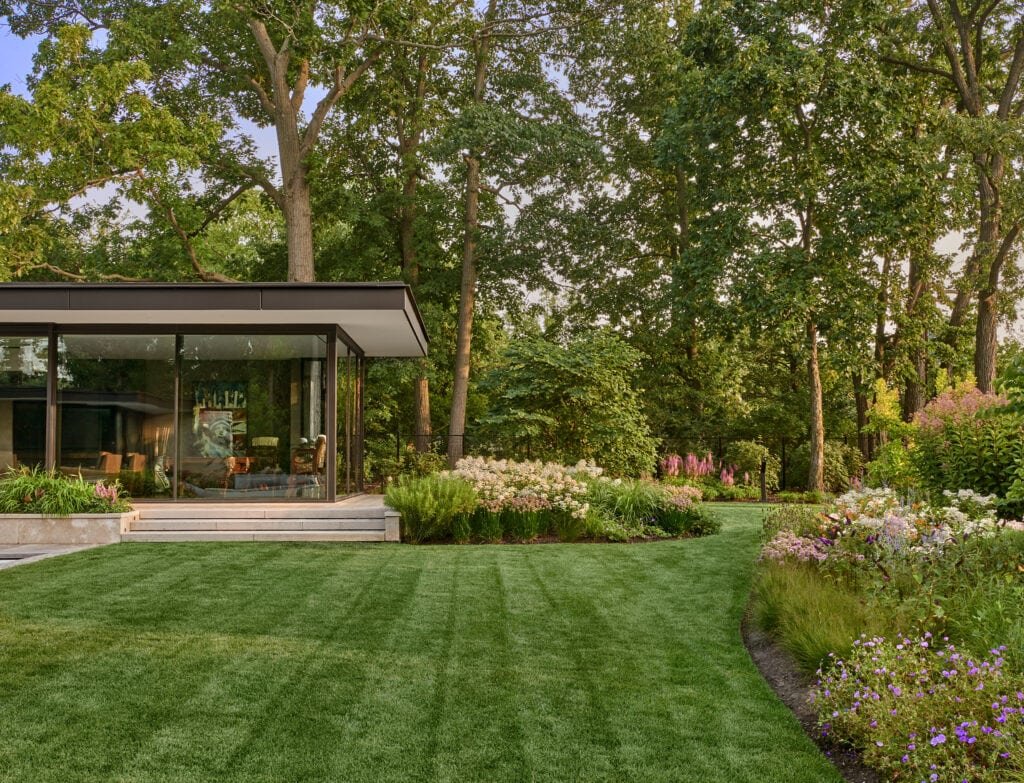 a modern home nestled on a lush lawn, surrounded by pristine gardens. 